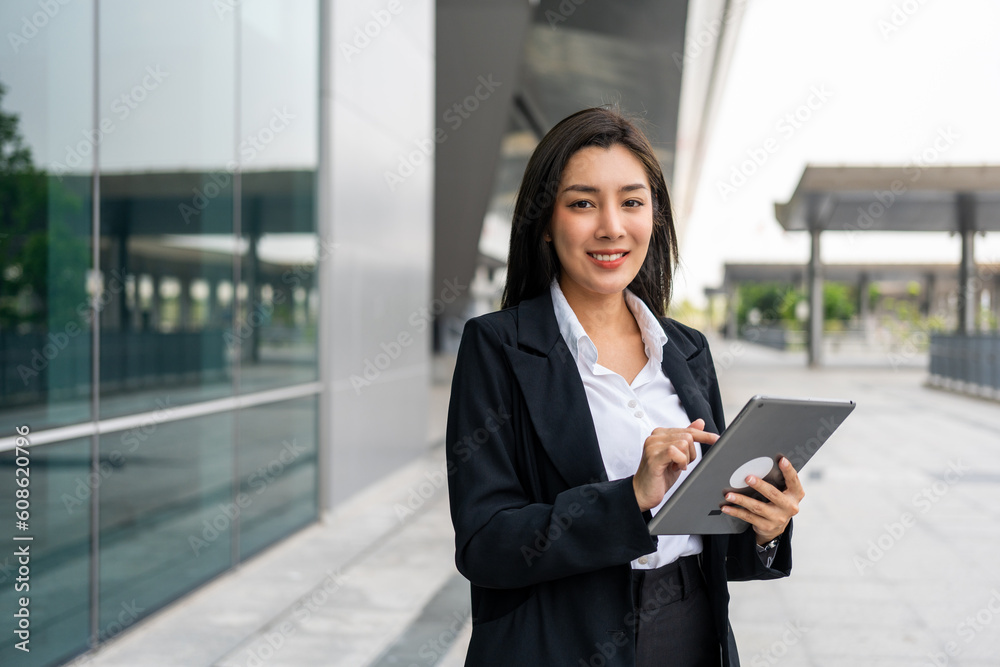 Portrait beautiful Businesswoman in suit with tablet standing at the buildings downtown. Confident woman using tablet. Executive Smart businessman