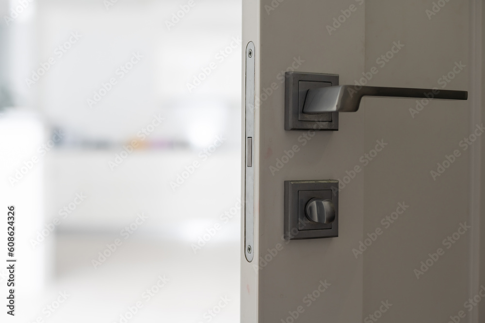 Chrome handle with keyhole on white door with panels in frames. Entrance. Close-up photo of architecture detail. Interior fragment as geometrical background with three rectangles and parallel lines Chrome handle with keyhole on white door with panels in frames. Entrance. Close-up photo of architecture detail. Interior fragment as geometrical background with three rectangles and parallel lines