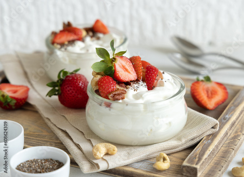 Glass jars of Greek yogurt, nuts and strawberries on a tray close up, copy space