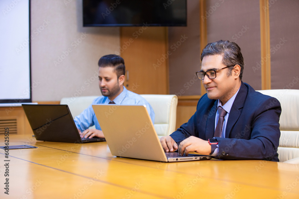 Young indian businessman using laptop an giving expression at office. Young indian businessman using laptop an giving expression at office.