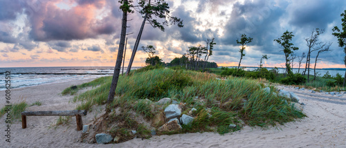 Fototapeta Naklejka Na Ścianę i Meble -  Spit on Lake Kopań. On the left, the Baltic Sea, on the right, the R-10 bicycle route and Lake Kopań. A beautiful spit with a sandy beach, dunes and coastal vegetation. Sunrise. Darlowo, Baltic Sea,
