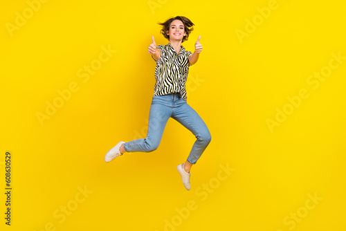 Full length photo of pretty confident woman dressed zebra striped shirt jumping high showing thumbs up isolated yellow color background