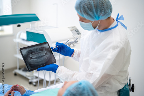 Schilderij op canvas Unrecognizable male dentist in medical uniform showing x ray image of teeth whil