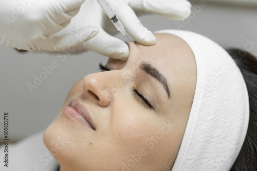 Injection with a syringe with butolin on a woman's face. Care with love: a woman visits a beautician for botulinum therapy, which makes her skin soft, smooth and youthful. Beauty clinic photo