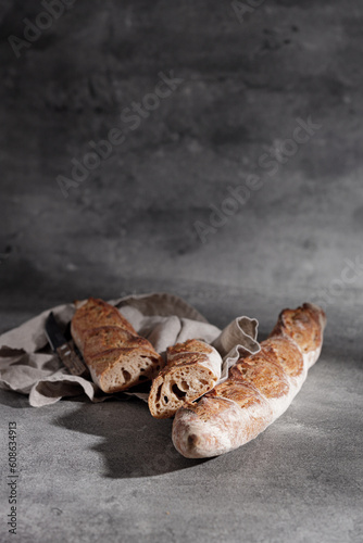 Fototapeta Naklejka Na Ścianę i Meble -  French baguette on a cotton towel on a grey background close-up. Free space for text