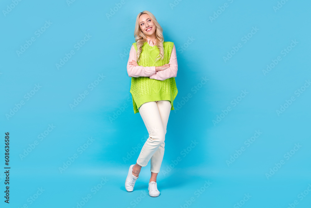 Full size photo of creative positive girl crossed arms look empty space isolated on blue color background Full size photo of creative positive girl crossed arms look empty space isolated on blue color background