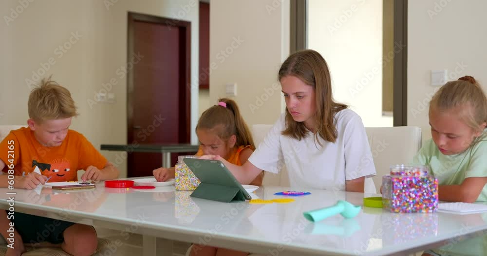 Four children, of variable age putting the mosaic together on the table Four children, of variable age putting the mosaic together on the table