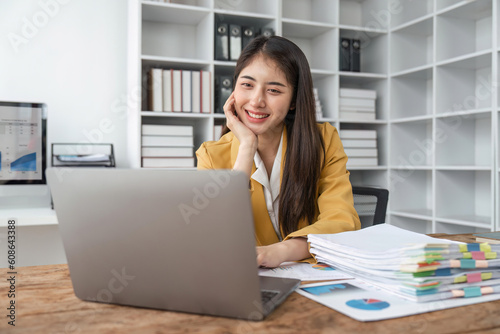 Cheerful happy business lady working on laptop in office