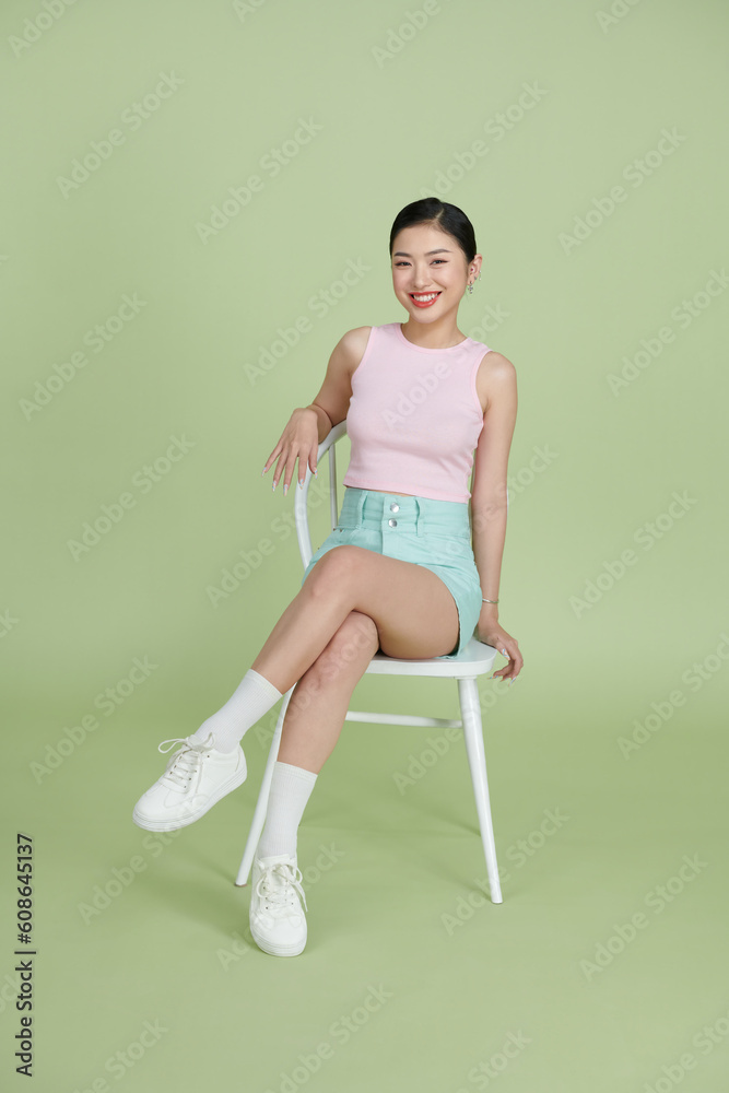 sweet pretty girl smiling sitting chair empty space isolated on mint color background sweet pretty girl smiling sitting chair empty space isolated on mint color background