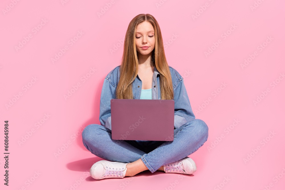 Photo of pretty cute girl wear stylish clothes sitting floor listening online lesson writing homework isolated on pink color background Photo of pretty cute girl wear stylish clothes sitting floor listening online lesson writing homework isolated on pink color background