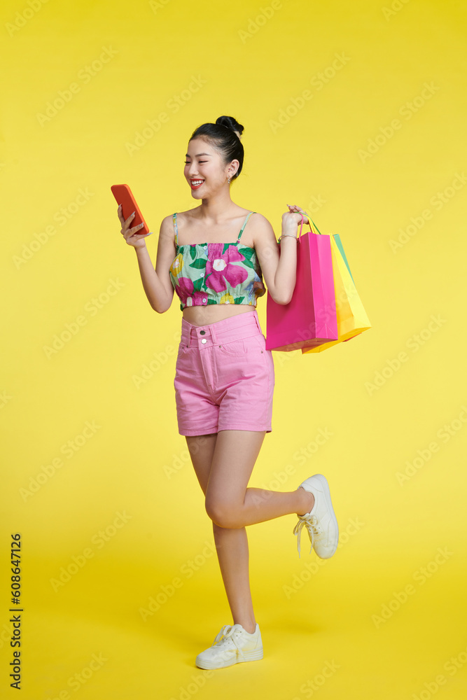 Beautiful asian woman are holding shopping bags and mobile phone with face happily Beautiful asian woman are holding shopping bags and mobile phone with face happily
