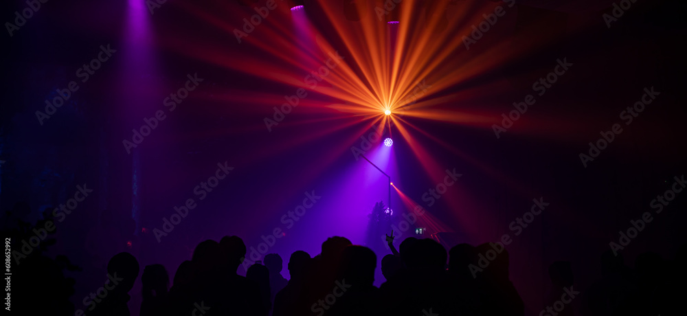 Background in show concert with orange beam yellow and blue spotlights. It is a striped gradient background in the concert.