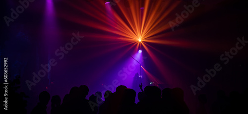Background in show concert with orange beam yellow and blue spotlights. It is a striped gradient background in the concert. © kaewphoto