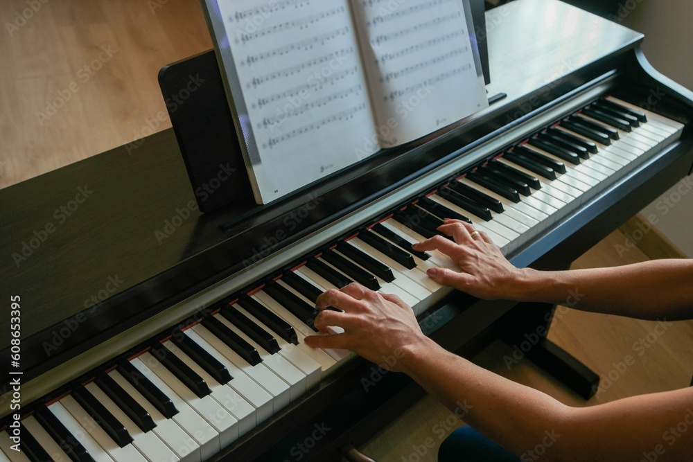 Alumna o profesora de piano tocando el instrumento donde se aprecia la digitación y close-up de sus manos. - obrazy, fototapety, plakaty 