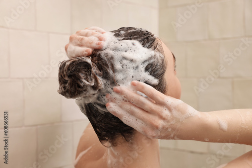 Young woman washing hair while taking shower at home