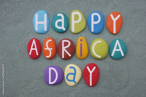 Happy Africa Day celebrated with hand painted stone letters over green sand