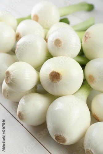Whole green spring onions on white wooden table  closeup