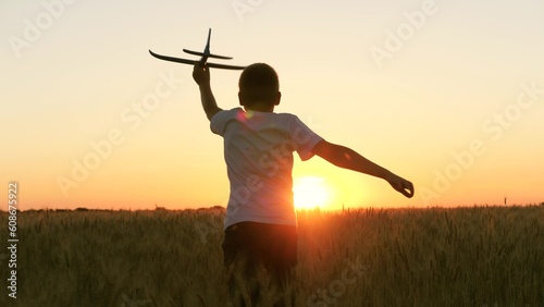 Photographie boy teenager child kid runs through field with wheat with toy plane his hands su