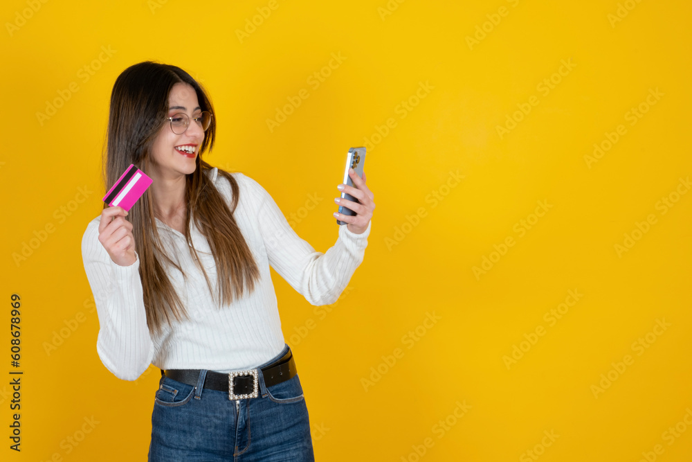 Using smartphone and holding credit card. Cheerful happy young caucasian girl paying online, shopping, e-commerce, internet banking, spending money, digital store concept idea image with copy space. Using smartphone and holding credit card. Cheerful happy young caucasian girl paying online, shopping, e-commerce, internet banking, spending money, digital store concept idea image with copy space.