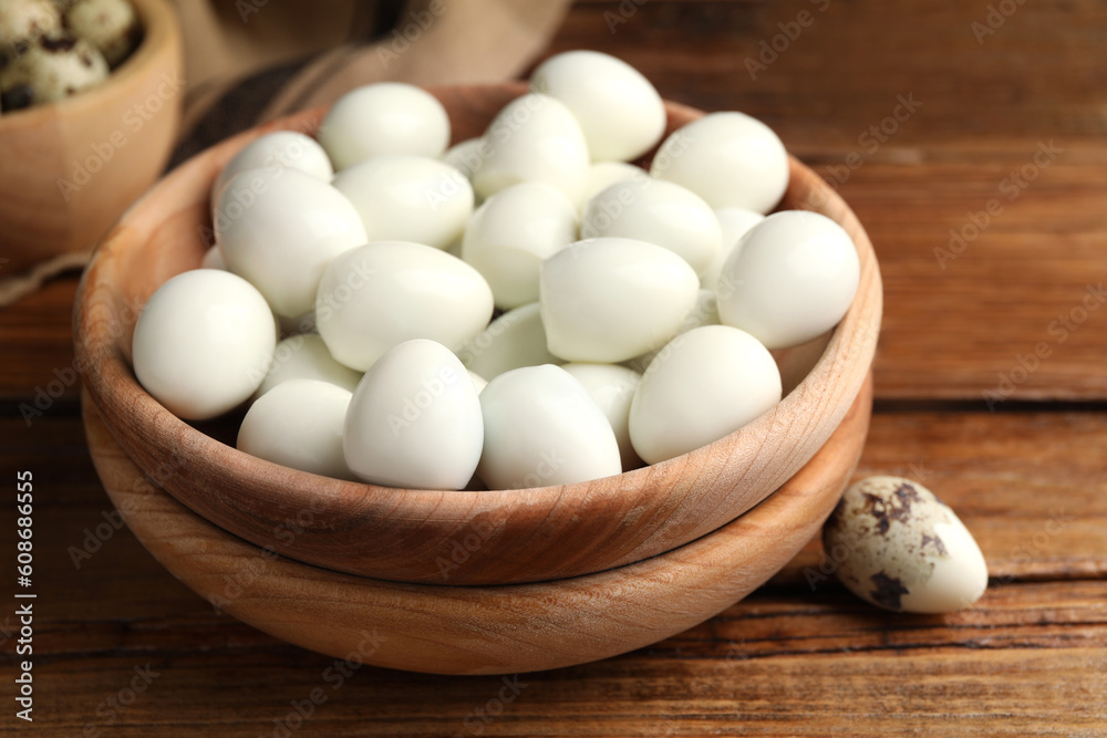 Many peeled boiled quail eggs and another one in shell on wooden table, closeup Many peeled boiled quail eggs and another one in shell on wooden table, closeup