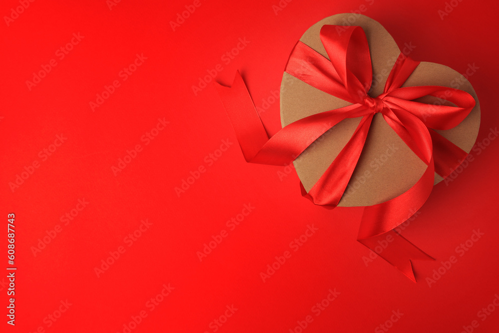 Beautiful heart shaped gift box with bow on red background, top view. Space for text Beautiful heart shaped gift box with bow on red background, top view. Space for text