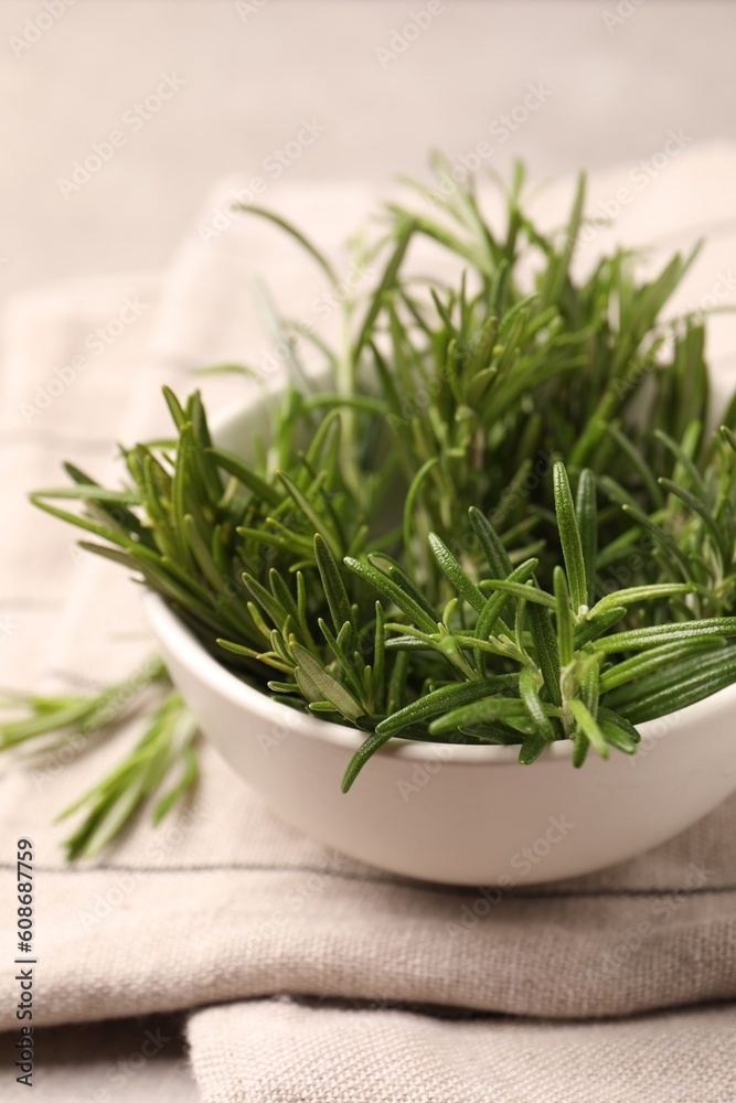 Bowl with fresh green rosemary on table, closeup