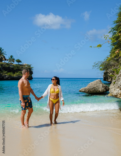 A couple of men and women at the beach of Playa Lagun Beach with a fishing boat at the Island of Curacao, Lagun Beach Curacao a small island in the Caribbean. 