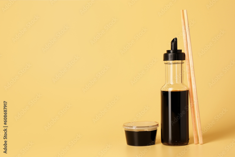 Soy sauce and chopsticks on yellow background, space for text