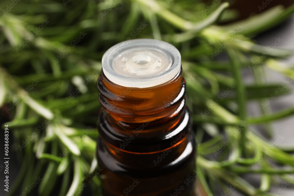 Bottle of rosemary oil on blurred background, closeup