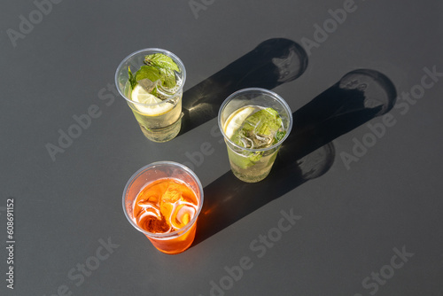 Topview of a grey table with drinks; Spritz and hugo in plastic glass; sunlight and shadows in the summertime