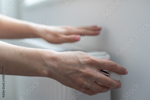 Close-up Of Woman's Hand Adjusting Radiator Thermostat Valve At Home
