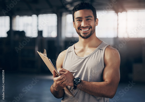 Fitness, clipboard and portrait of a personal trainer in the gym working on a training schedule. Confidence, happy and male athlete writing a workout or exercise plan for wellness in a sports center.