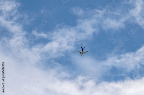 A plane is flying in a blue sky with clouds