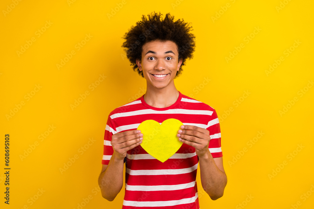 Photo of funky cheerful guy dressed red t-shirt holding arms heart isolated yellow color background Photo of funky cheerful guy dressed red t-shirt holding arms heart isolated yellow color background