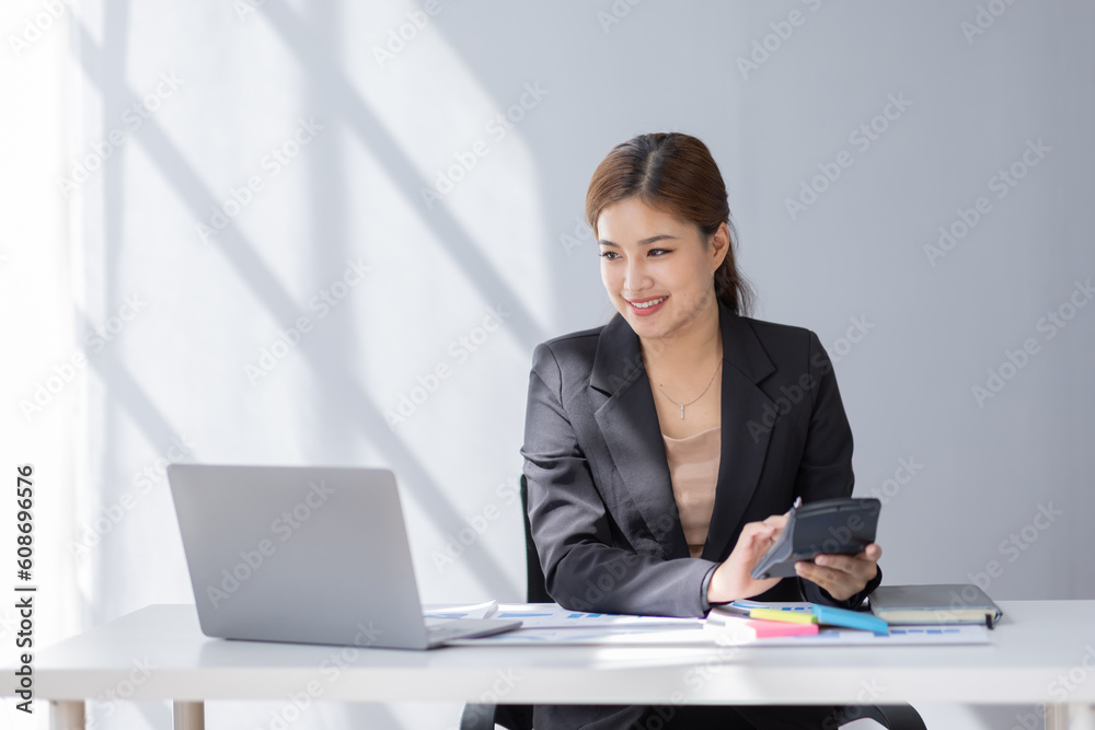Asian student business woman using calculator and laptop for doing math finance on an office desk, tax, report, accounting, statistics, and analytical research concept Asian student business woman using calculator and laptop for doing math finance on an office desk, tax, report, accounting, statistics, and analytical research concept