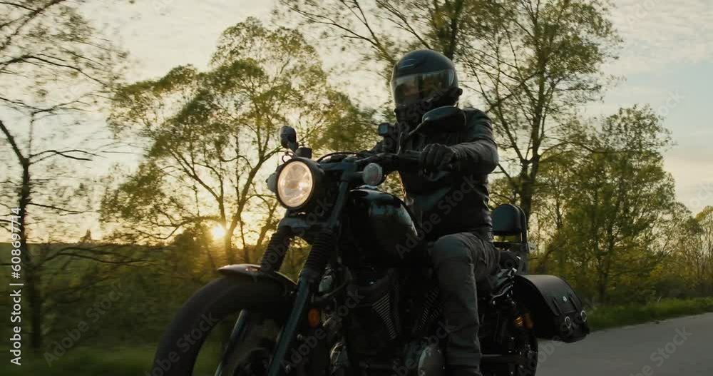 Low-angle shot of a biker riding a black motorcycle during a beautiful sunset. Low-angle shot of a biker riding a black motorcycle during a beautiful sunset.