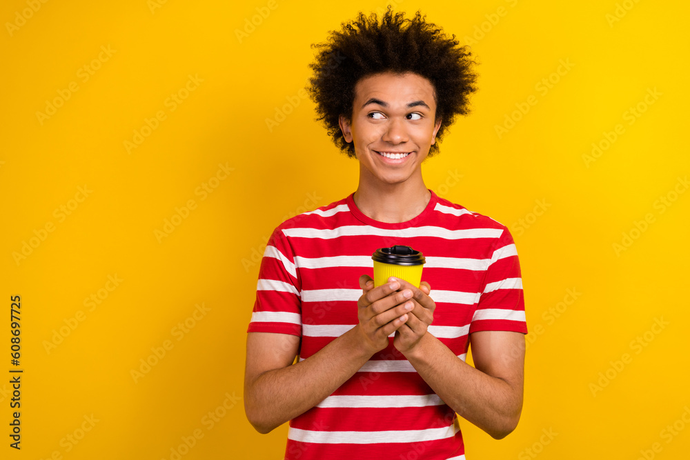 Photo of attractive tricky guy wear striped t-shirt enjoying coffee looking empty space isolated yellow color background Photo of attractive tricky guy wear striped t-shirt enjoying coffee looking empty space isolated yellow color background