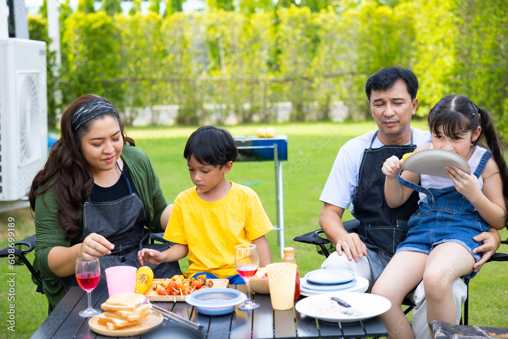Home camping and cooking Barbeque party. Happy Asian family enjoying BBQ camping at home. Asian family in backyard garden at home.