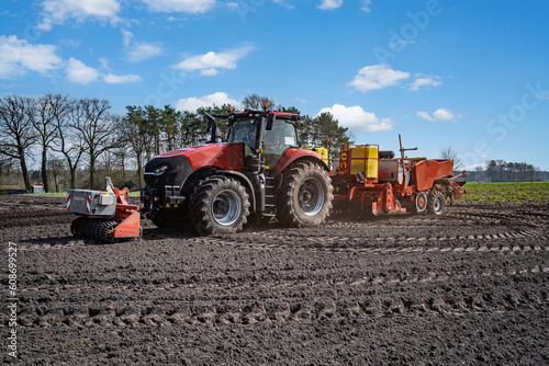 Modernes Kartoffellegegerät mit Traktor im Frühjahr auf dem Kartoffelfeld im Einsatz. 