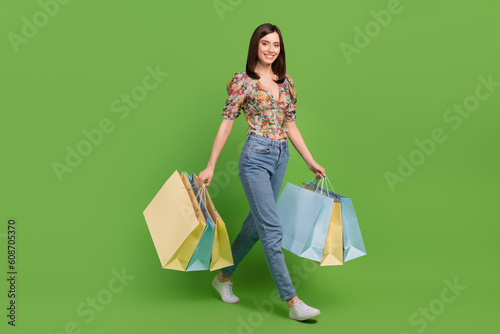 Full length photo of young girl shopping lover advert new bershka collection clothes walk with bargains isolated on green color background photo
