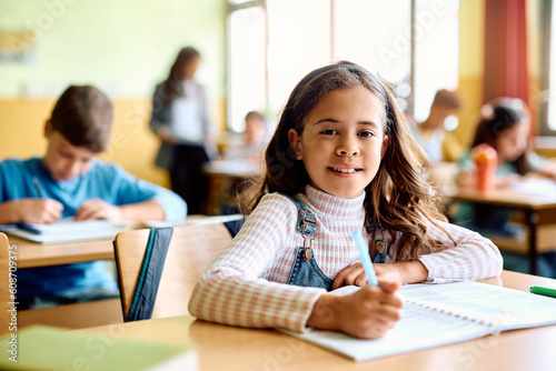 Happy Hispanic girl learning during class at elementary school and looking at camera.