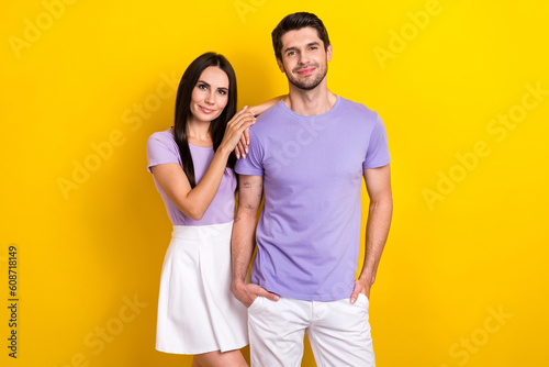 Portrait of two friendly satisfied people hug have good mood isolated on yellow color background