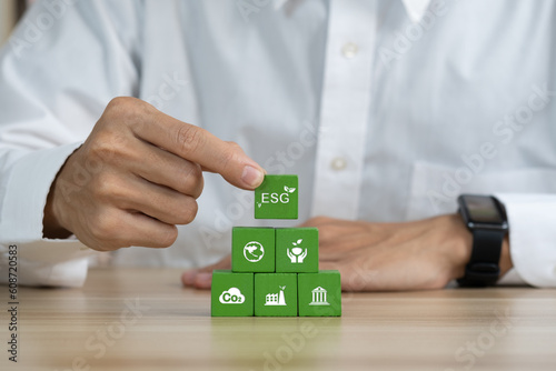 Hand flips wooden cubes with target setting to ESG icon with other ESG icons on bright background. Copy space. ESG concept of environmental, social and governance.