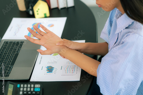 Successful business woman sitting in the office Using a laptop to work so hard that it hurts her wrists. De Quervain s tenosynovitis, ergonomic, Carpal Tunnel Syndrome or Office syndrome concept photo