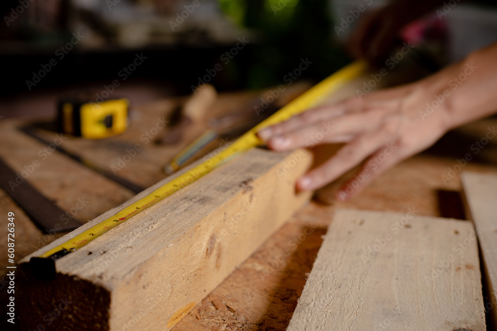 Female use tape measure to assemble wooden pieces. Professional carpenter at work measuring wooden planks. Female use tape measure to assemble wooden pieces. Professional carpenter at work measuring wooden planks.