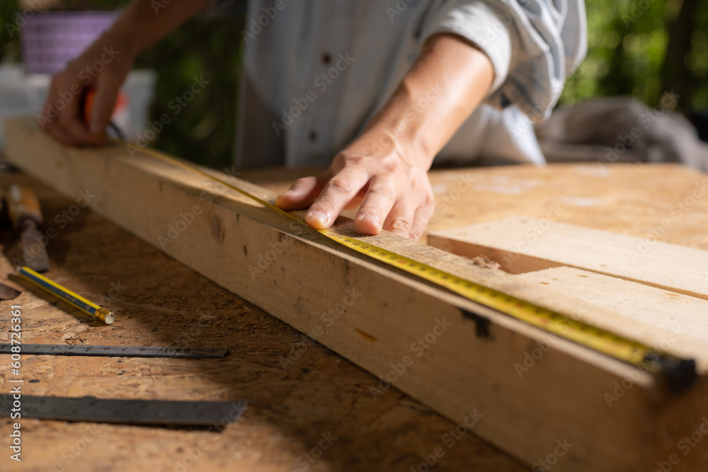 Female use tape measure to assemble wooden pieces. Professional carpenter at work measuring wooden planks. Female use tape measure to assemble wooden pieces. Professional carpenter at work measuring wooden planks.