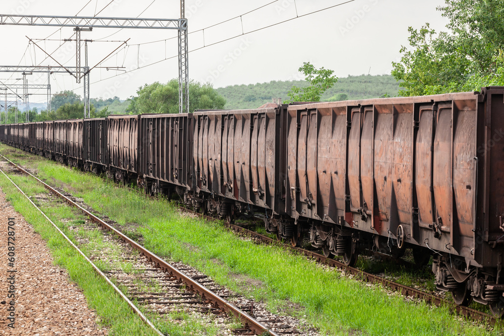 Obraz premium Coal train made of Open Wagons, also called Gondola wagons, rusty, waiting on a freight railway station, half abandoned, in Serbia, in a former cargo and industrial hub of the region.