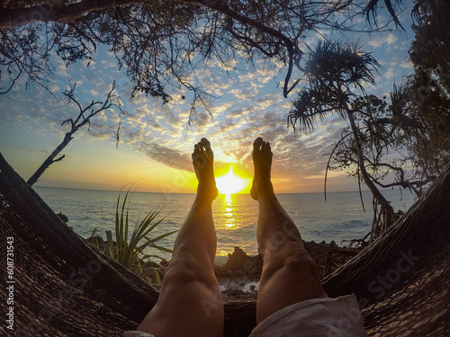 person lying in a hammock with feet in the air on an African beach before dinner