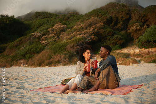 Smiling young multiethnic couple talking on a sandy beach at sunset
