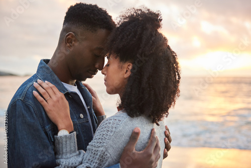 Affectionate multiethnic couple standing with closed eyes on a beach at dusk